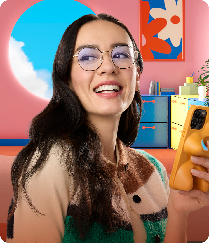 Persona con Lentes Zenni redondas y un teléfono en una habitación colorida.