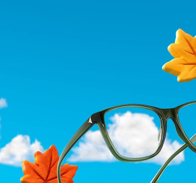 Close-up of Zenni olive square glasses against a blue sky with colorful fall leaves.