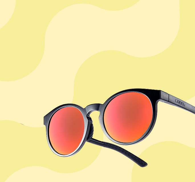 Round black sunglasses with vibrant orange reflective lenses floating against a light yellow background with abstract wavy patterns.