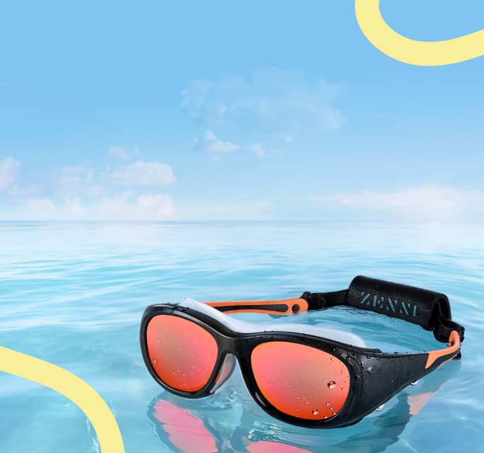 Black wrap-around sports sunglasses with red mirror finish Zunscreen sun lenses, a removable buoyancy strap, a rubber inner seal, and orange rubberized temples. Water and blue sky background.