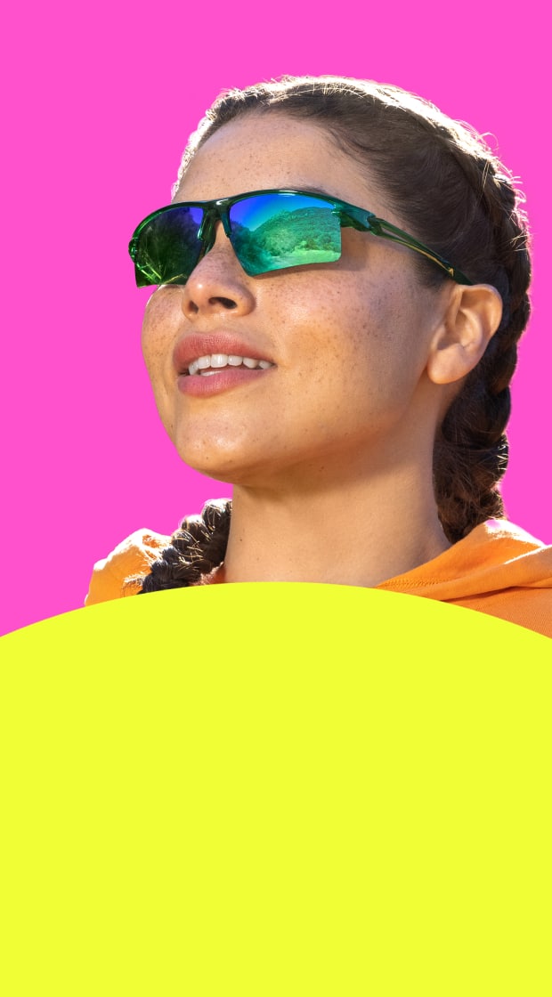 Girl wearing Zunnies sports sunglasses with classic tinted lenses against a pink and yellow background.
