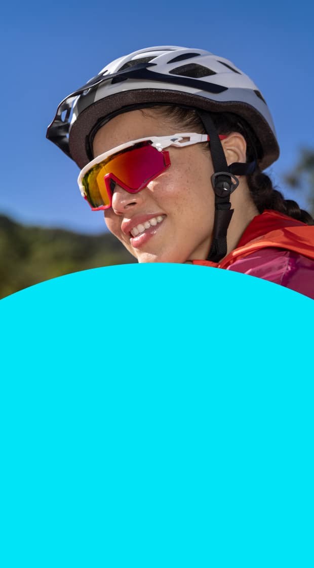 Woman outside wearing a cycling helmet and Zunnies cycling sunglasses with red mirrored lenses.