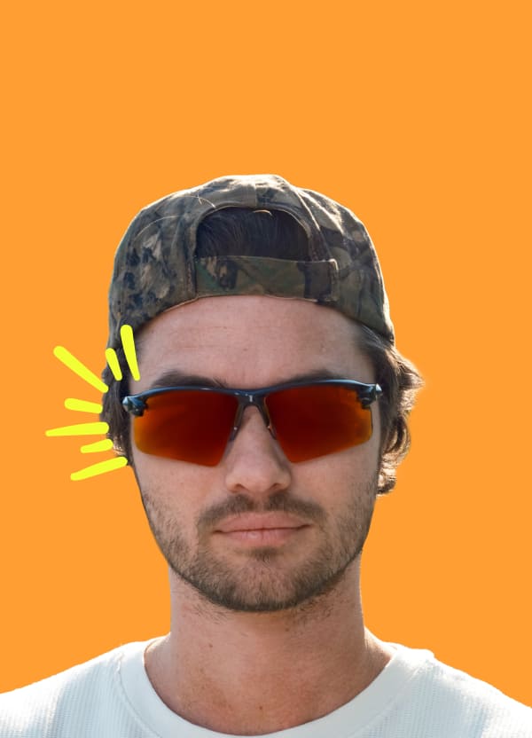 Chase Stokes in mirrored Zunnies sunglasses, against a vibrant orange background.