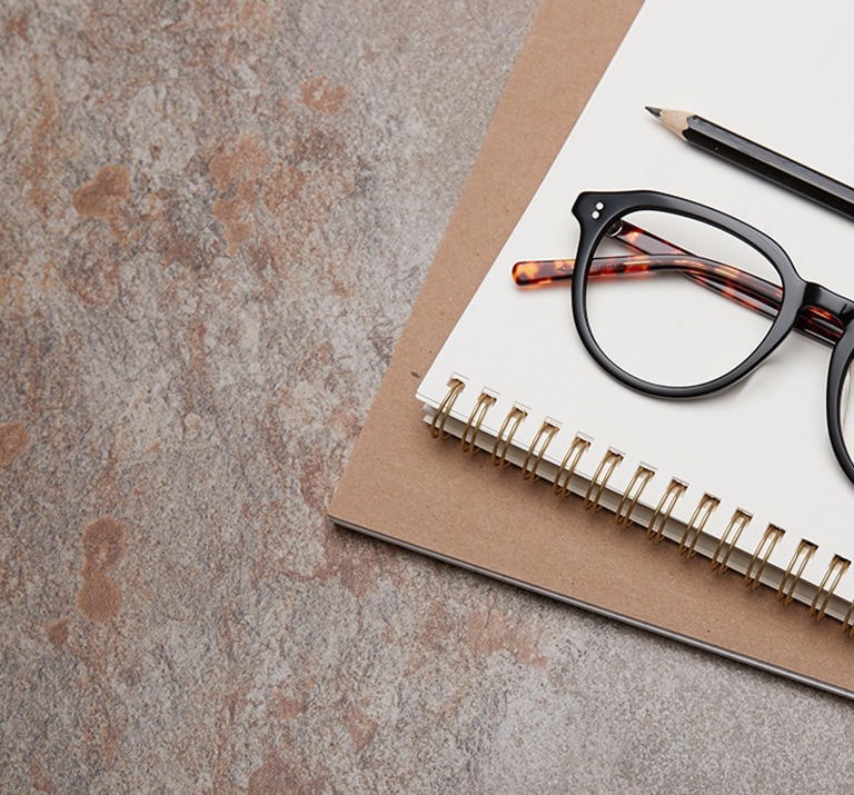 Round glasses #4432921 sit next to a black pencil atop a spiral bound notebook on a quartz background.