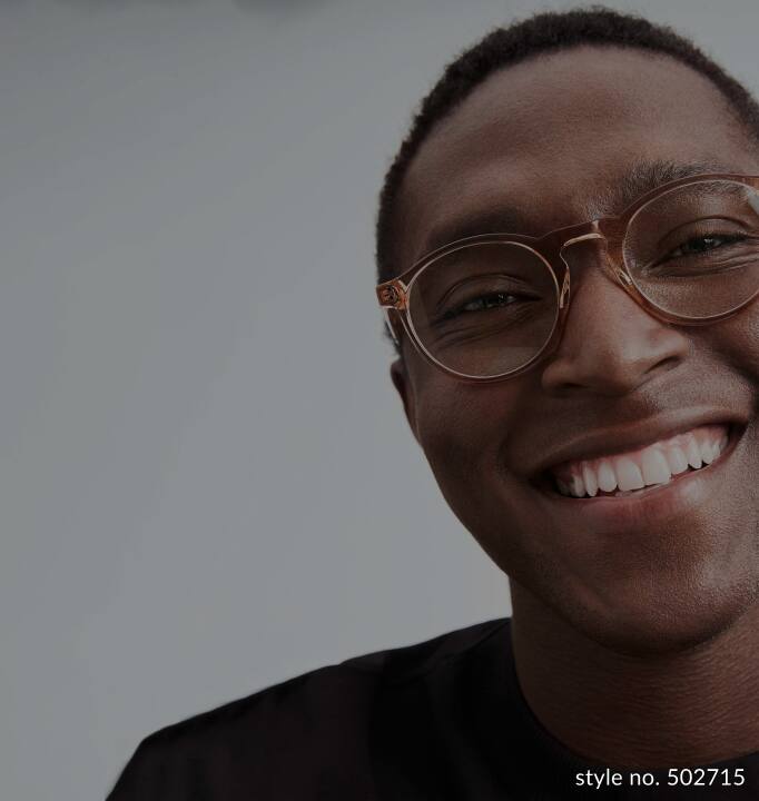 Image of a man wearing Zenni round glasses, smiling against a gray background.