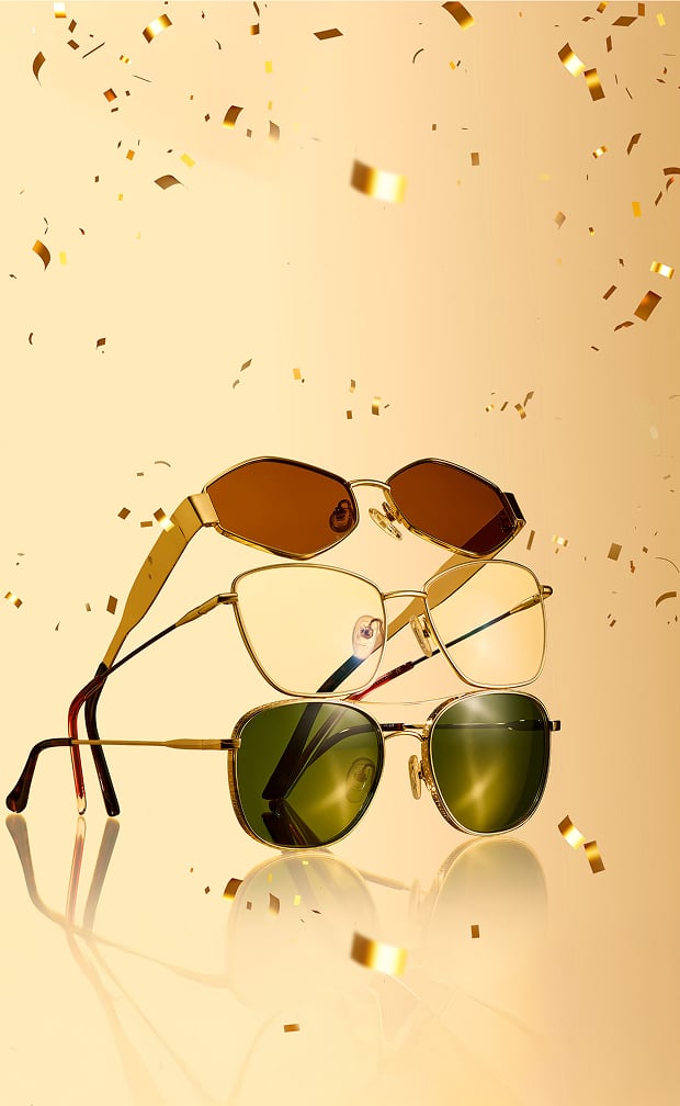 A collection of gold and bronze eyeglasses and sunglasses arranged stylishly on a reflective gold surface.