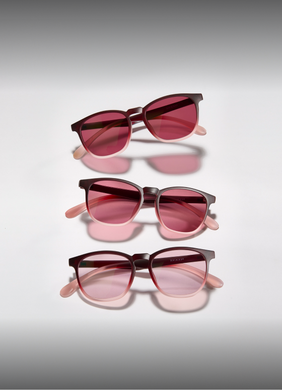 A trio of Zenni FL-41 rose-tinted migraine glasses, neatly arranged and reflected on a white surface.