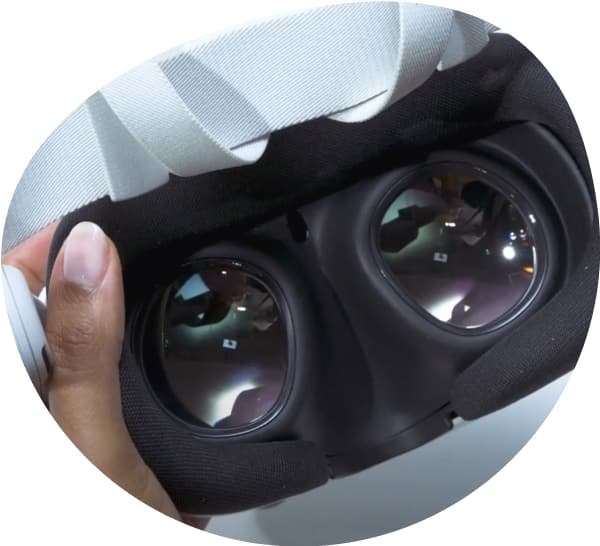 Image of a hand holding a Meta Quest 3 VR headset, looking at the interior view of the VR lenses.