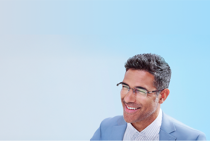 Blonde woman in peach-tinted rimless glasses with white paper sheets flying around her on a blue background.