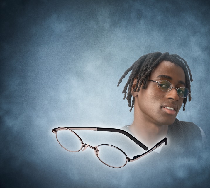 Close-up of a young person with braided dark hair looking forward while wearing thin oval wireframe eyeglasses, positioned next to an identical pair of floating eyeglasses against a smoky slate blue background.