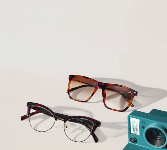 Image of two pairs of glasses, one is a pair of large square frames with tinted lenses and a pair of cat-eye glasses with clear lenses and dark red tortoiseshell frames, alongside a teal camera.