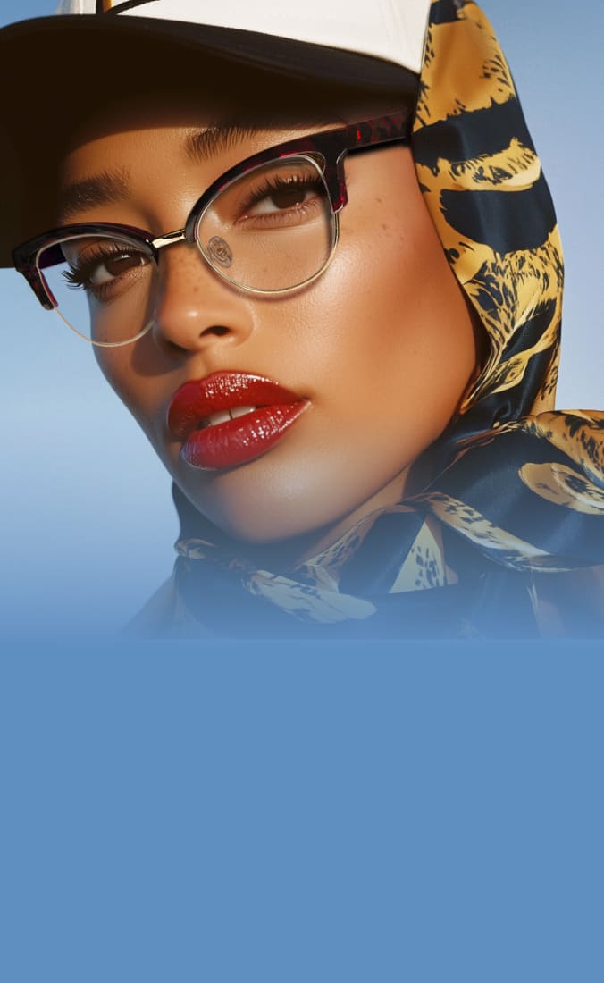 Image of a person wearing tortoiseshell cat-eye glasses with clear lenses, a baseball cap, and a silk scarf with a gold and navy pattern. They have glossy red lips and glowing skin against a bright blue background.