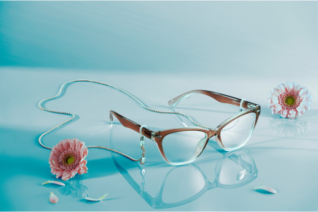 Brown gradient cat-eye glasses with silver eyeglass chains on a blue background.