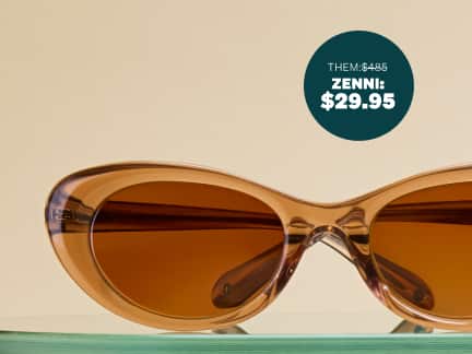 Brown transparent cat-eye sunglasses with brown lenses, sitting on a glass shelf on a beige background. 