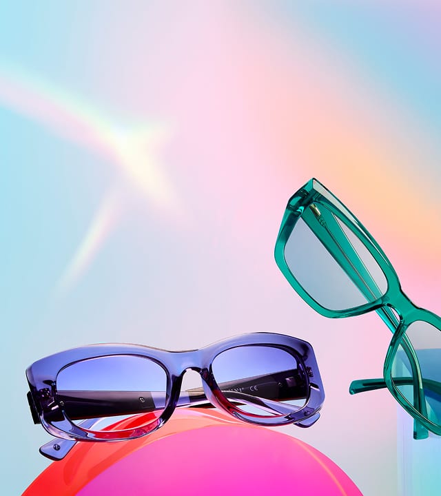 Blue and green Zenni Summer Brights glasses on a colorful background with a pink orb.