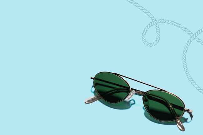 A pair of round aviator sunglasses on a light blue background.