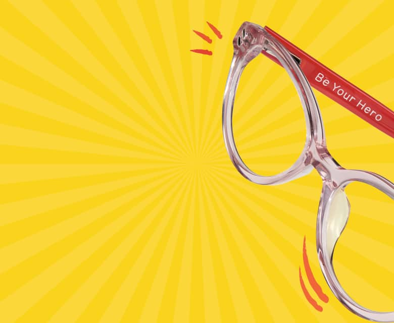 A pair of transparent eyeglass frames with red arms, one of which is engraved with the words 'Be Your Hero,' set against a yellow background with red accents.