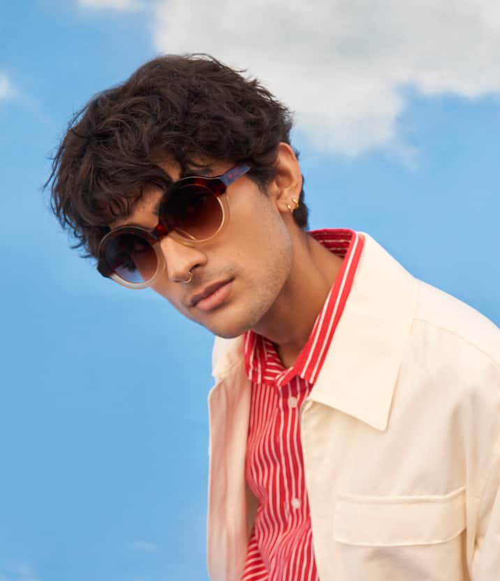 Close-up showing the midsection of a person wearing a red and white striped shirt, brown pants, and a cream-colored jacket.