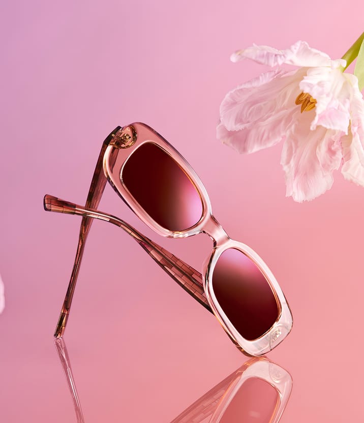A product photo of beige Zenni Rectangle Glasses against a light pink background with a wispy white flower.