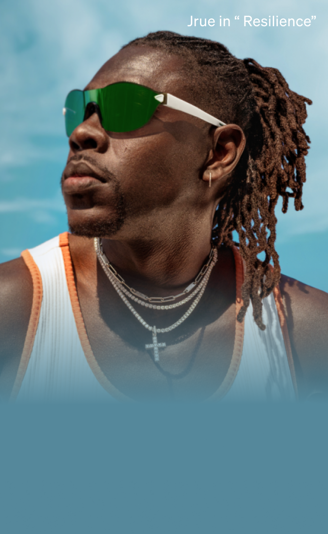 Jrue Holiday wearing reflective green sunglasses, a white tank top with orange trim, and multiple necklaces, standing outdoors under a clear blue sky, with a red basketball hoop in the background.