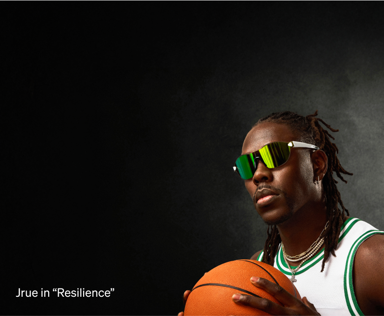 Jrue Holiday wearing Zenni glasses in a green and white jersey, holding a basketball in front of him.