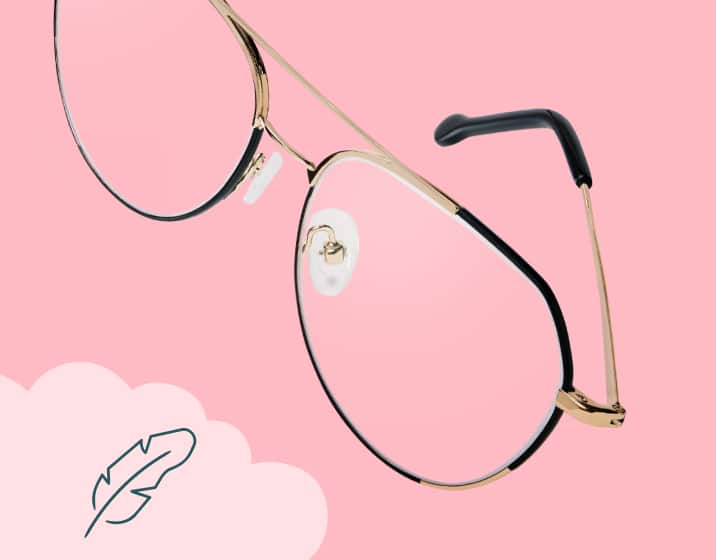 Black and gold aviator glasses floating on a pink background. An illustrated feather in the bottom left corner indicates the frames are lightweight.