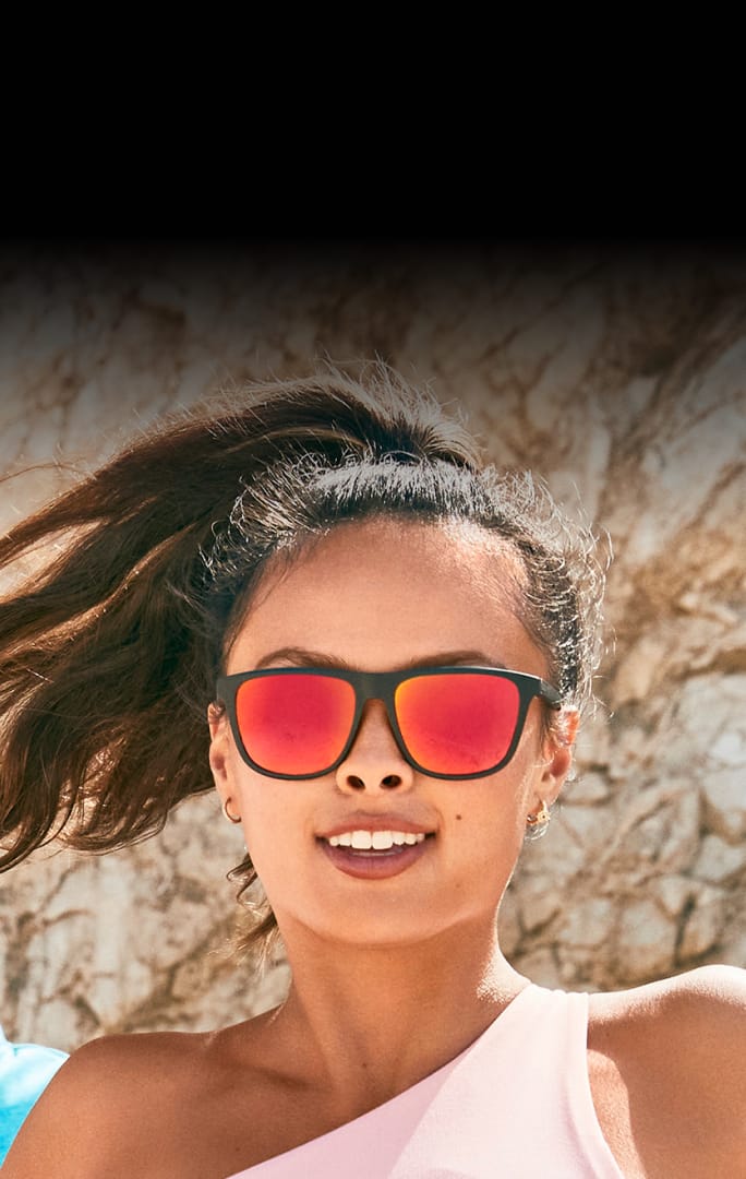 A woman wearing dark Zenni sunglasses outdoors with text highlighting the sports performance of impact-resistant lenses.