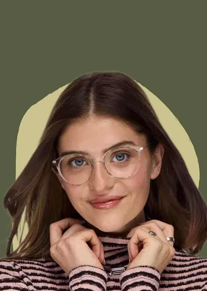 Smiling woman wearing clear round eyeglasses and a striped turtleneck sweater against an olive green background.