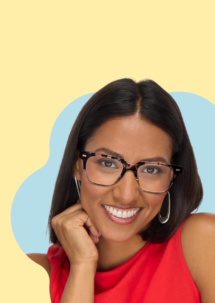 A woman with dark hair smiling and resting her chin on her hand, wearing thick-rimmed tortoiseshell rectangle glasses against a blue and yellow cloud-shaped background.