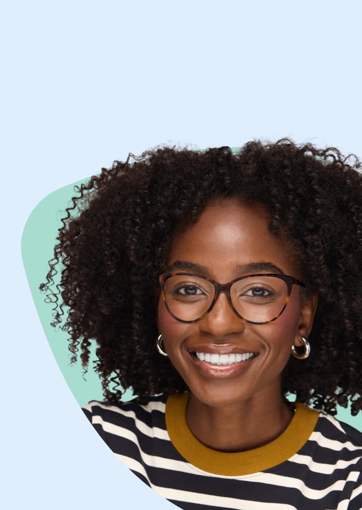A woman with curly dark hair smiling, wearing thin dark cat-eye glasses against a pale green and blue cloud-shaped background.