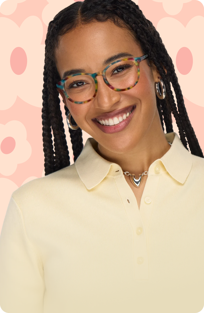 A smiling woman with long dark braids wearing round, multi-colored tortoiseshell glasses against a soft pink background with large flower illustrations.