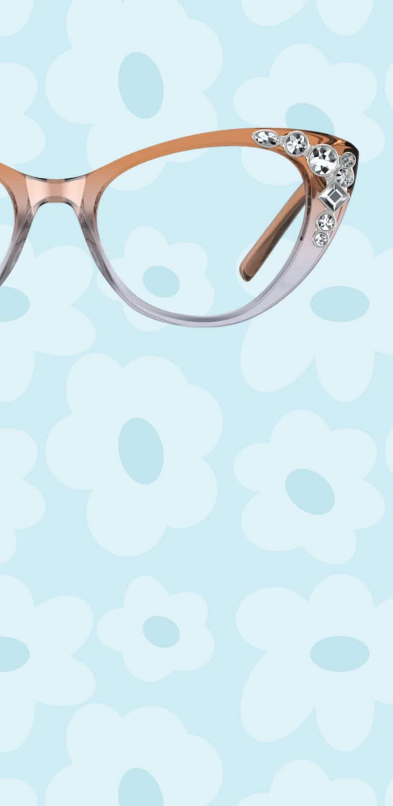 A pair of translucent rose-to-clear gradient cat-eye glasses with sparkling crystal embellishments on the outer corners, centered against a light blue background with white flower outlines.