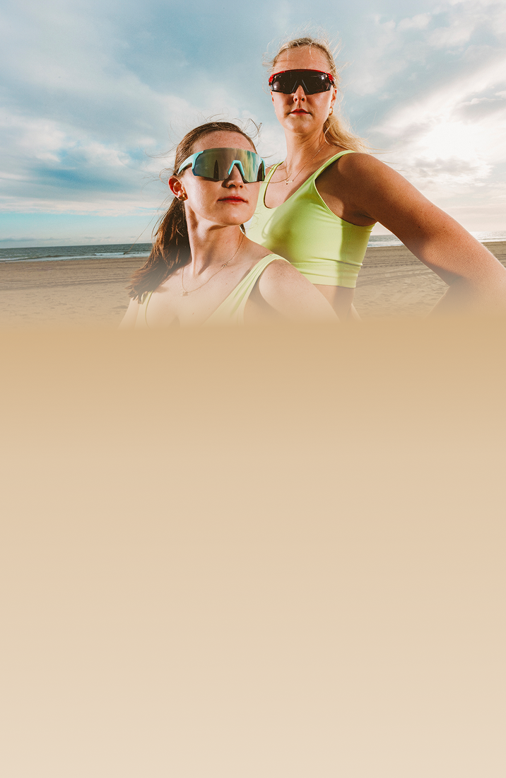 Taryn Kloth and Kristen Nuss wearing sports sunglasses on a beach, with the text 'Sports Sunglasses Built For Peak Performance' and options to 'Shop now' or 'Learn more.