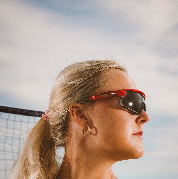 Taryn Kloth wearing red sunglasses with the quote, 'The adjustable nose helps my frames stay in place, always.' Background shows an outdoor setting. 'Shop now' button below the quote.
