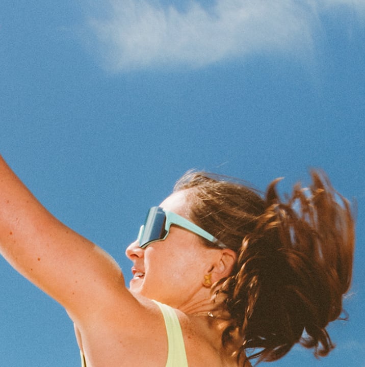 Kristen Nuss wearing sunglasses with the quote, 'I love how the lens reduces glare so I can spot the ball quicker.' Background shows an outdoor setting under a blue sky. 'Shop now' button below the quote.
