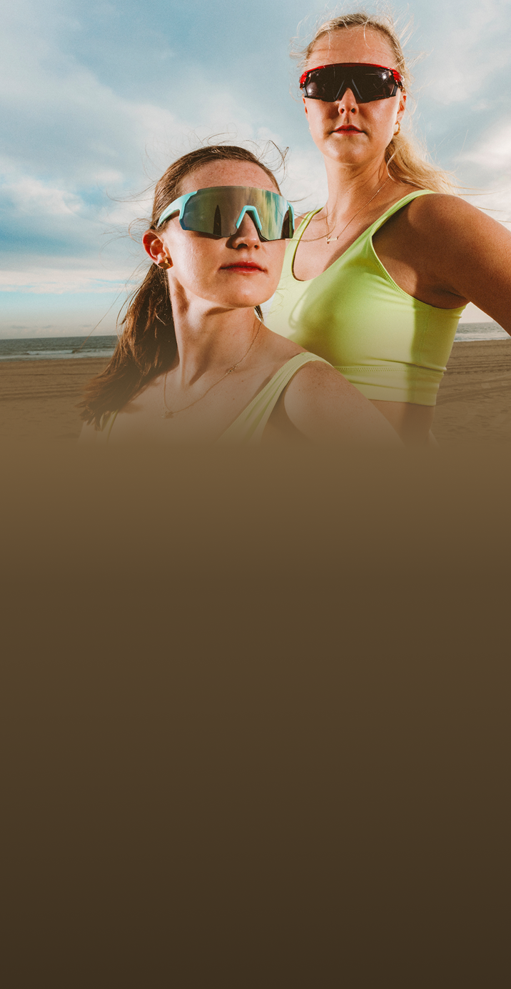 Taryn Kloth and Kristen Nuss wearing sports sunglasses on a beach, with the text 'Sports Sunglasses Built For Peak Performance' and options to 'Shop now' or 'Learn more.