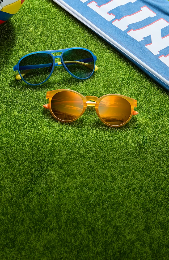 Zenni blue and yellow sunglasses on grass next to a soccer scarf.