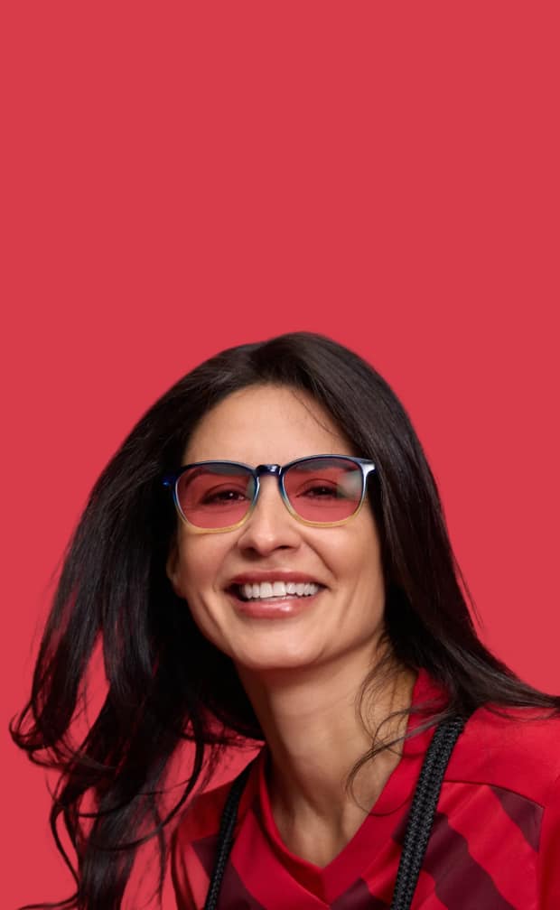 Woman wearing Zenni rose-tinted FL-41 glasses against a red background.
