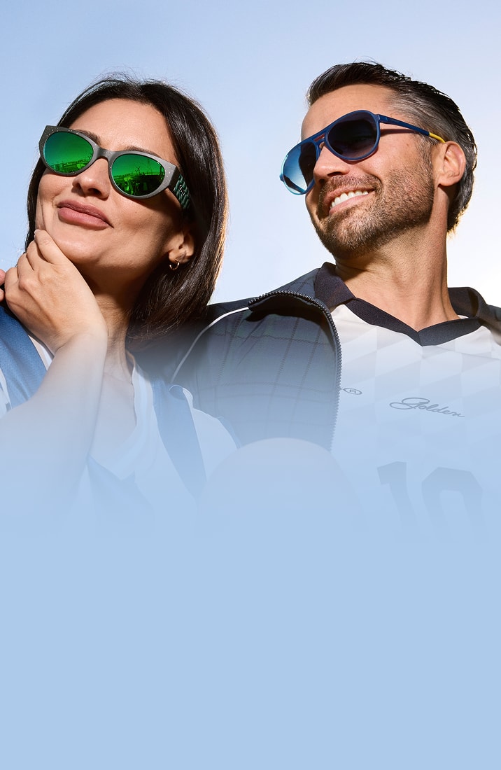 Two adults wearing Zenni sunglasses and soccer jerseys, smiling outdoors on a sunny day.