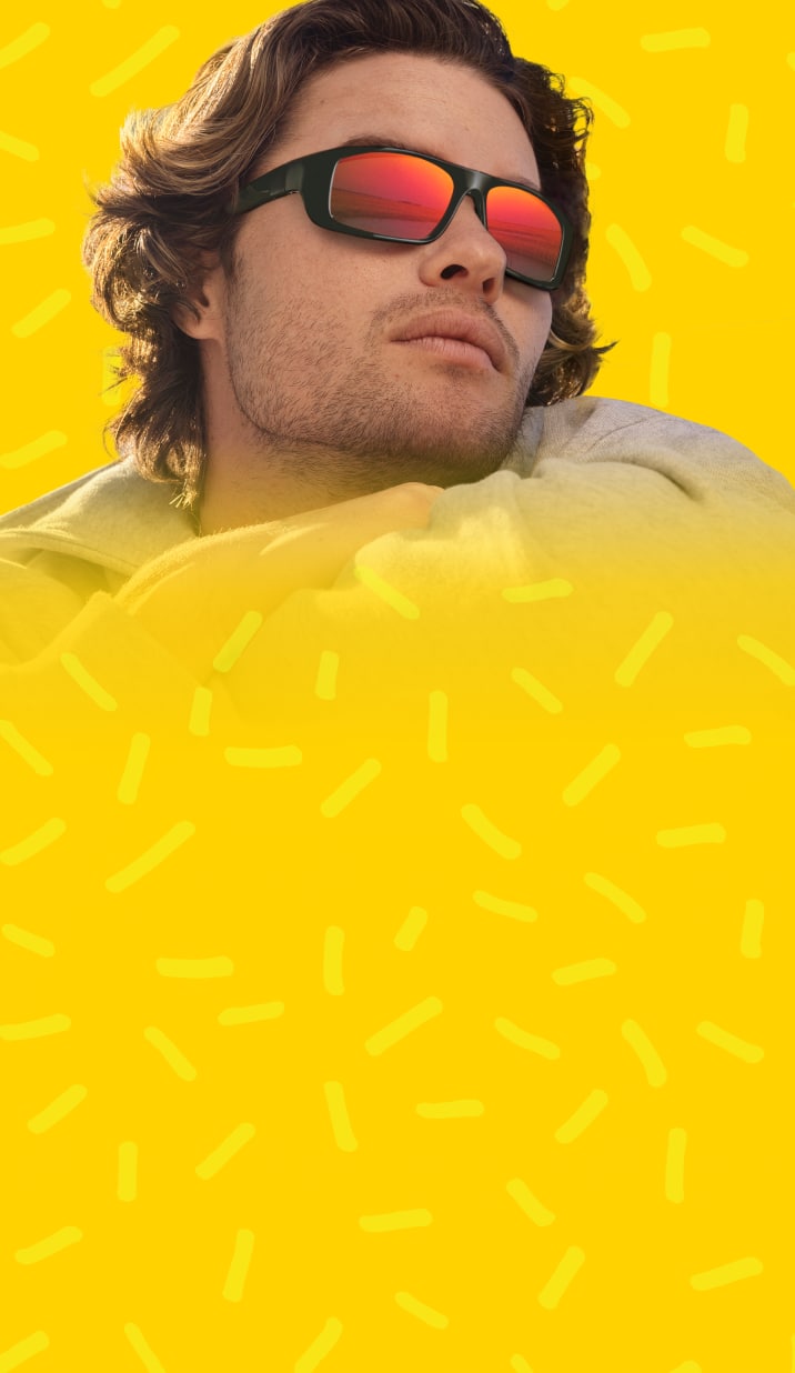 Chase Stokes wearing mirrored Zunnies sunglasses against a bright yellow background with playful graphic accents.