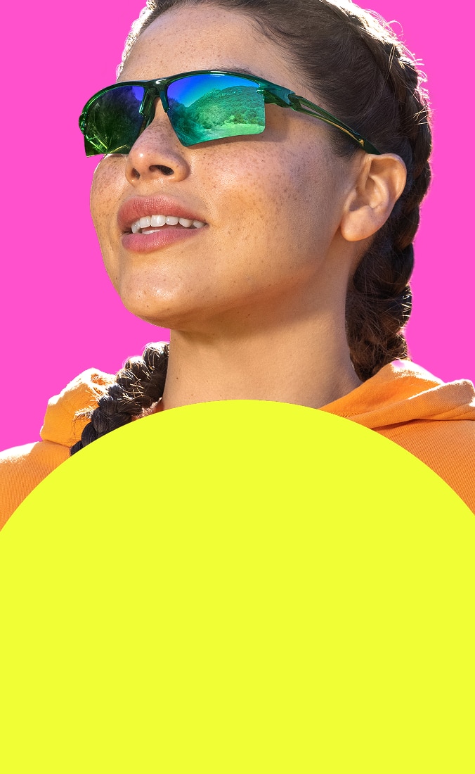 Girl wearing Zunnies sports sunglasses with classic tinted lenses against a pink and yellow background.