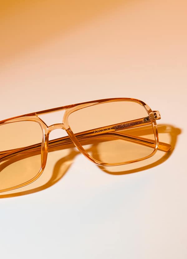 Orange Zenni translucent eyeglasses On light orange background.