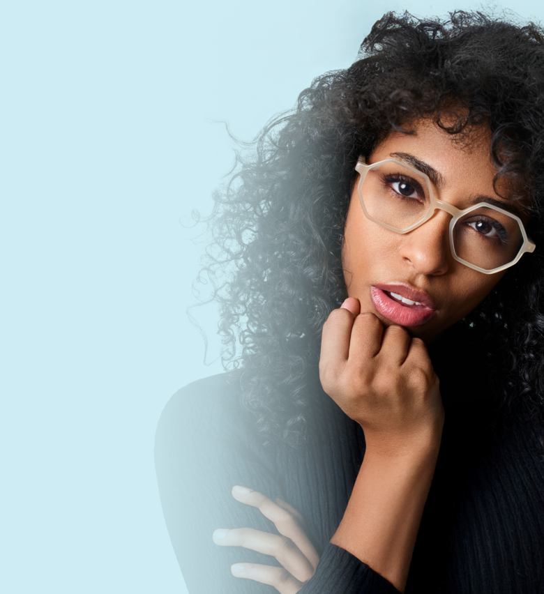 Woman with curly hair wearing large geometric Zenni glasses against a light blue background.