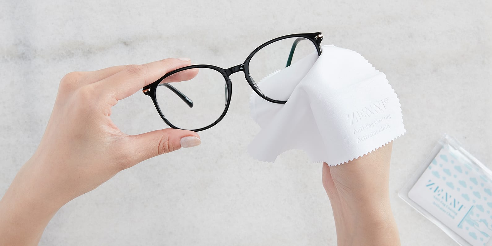 Image of the person wiping the glasses with Zenni's Anti-fog Activiator Cloth.