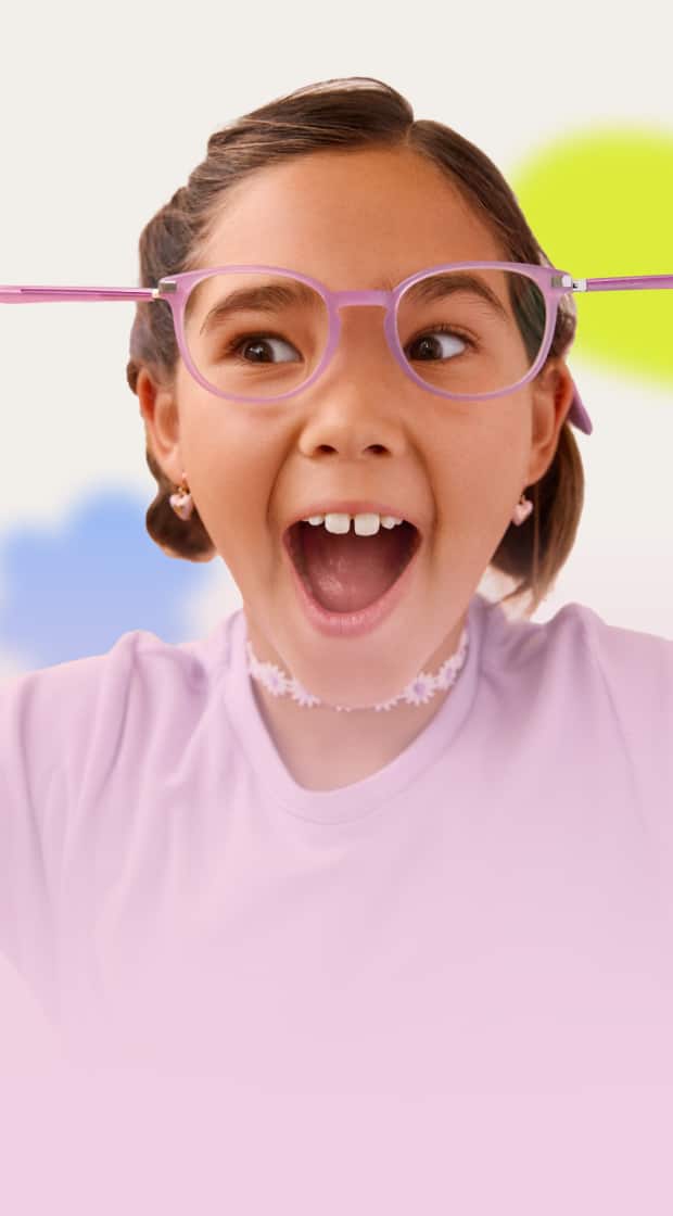 A young girl with pigtails excitedly stretches her pink glasses outward, wearing a lavender shirt and floral choker, with colorful blurred shapes in the background.