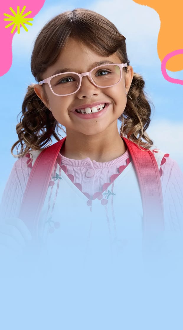 Smiling young girl with pigtails wearing light pink eyeglasses against a blue sky background.