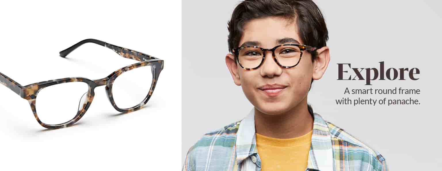 Boy with brown hair wears tortoiseshell Explore round glasses #4440935 with a pale madras shirt over a yellow tee.