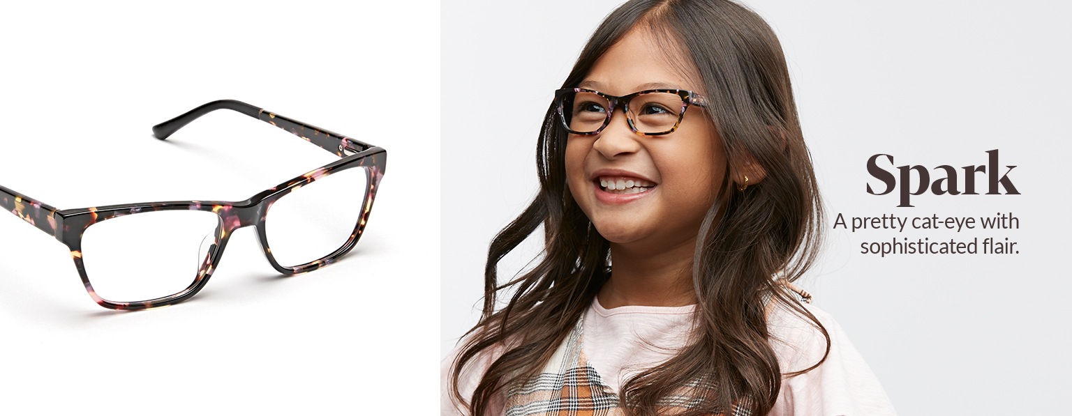 Young girl with long brown hair wears tortoiseshell Spark cat-eye glasses #4440225 with plaid jumper over a pink tee.