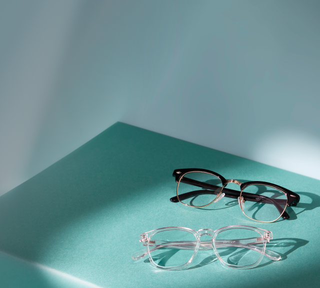 2 pairs of browline and clear plastic glasses on a teal shelf.