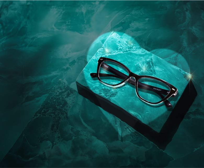 A chic pair of cat-eye black glasses rests on a textured turquoise surface.